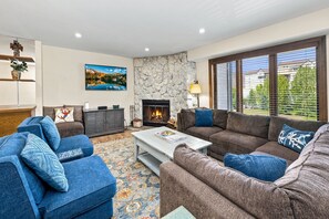 A living room with a stone fireplace, two sofas, a coffee table, and a painting on the wall.
