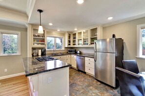 A modern kitchen with a central island, stainless steel appliances, and a view of the outdoors.