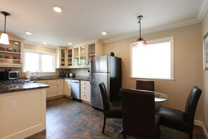 Kitchen features a central island with a stove, microwave, and sink, as well as a dining area with two chairs.