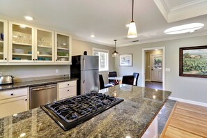 A modern kitchen with a central island, stainless steel appliances, and a dining area with a glass table.