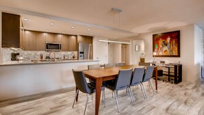 Une cuisine moderne dotée d’un îlot central, d’appareils électroménagers intégrés et d’un coin repas avec une table et des chaises en bois.