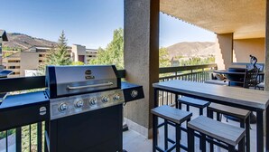 Une terrasse extérieure avec un barbecue, une table et des chaises.