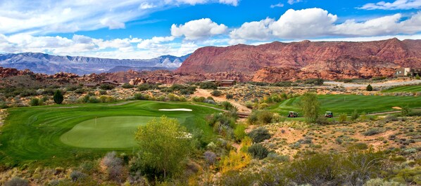 A golf course with a desert landscape and mountains in the background.