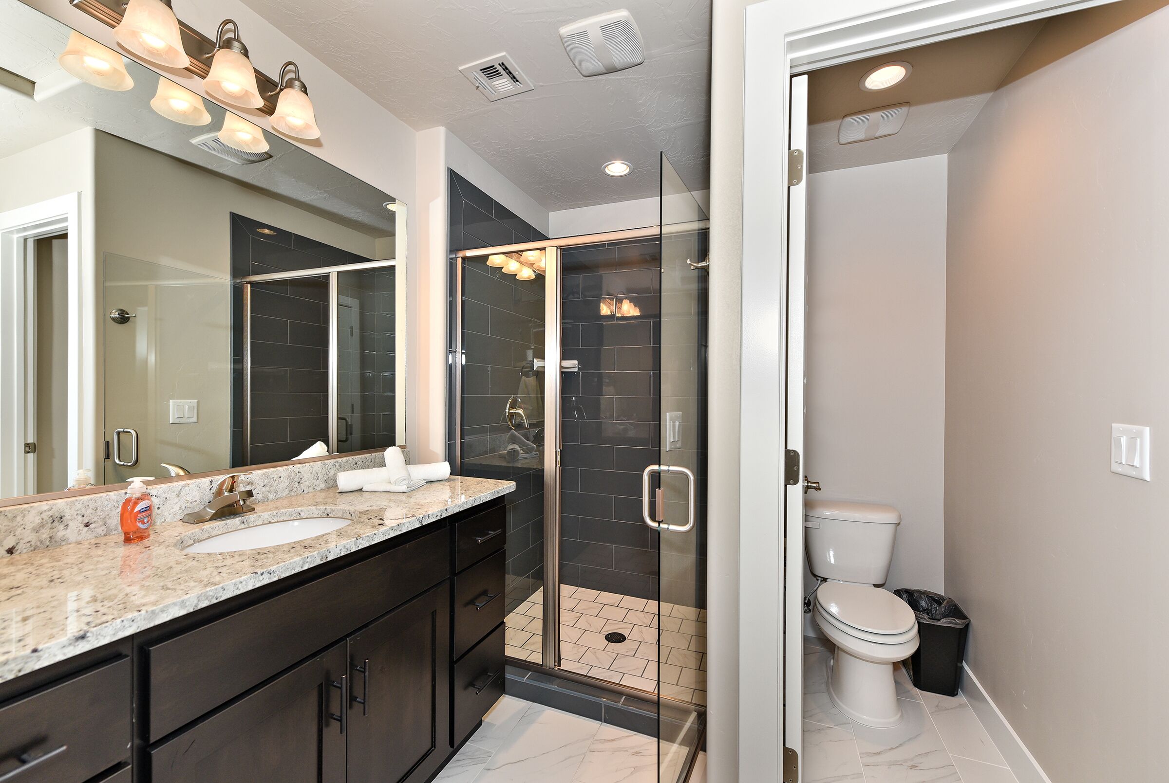 A modern bathroom with a glass-enclosed shower, a double sink vanity, and a toilet.