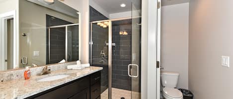 A modern bathroom with a glass-enclosed shower, a double sink vanity, and a toilet.