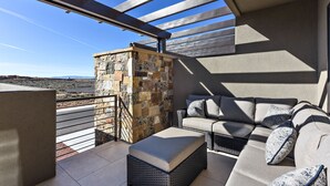 A balcony with a stone wall, a wicker sofa, and a cushioned bench. - Spacious 3BR Sleeps 10 - Poolside on the 9th Hole (St. George)