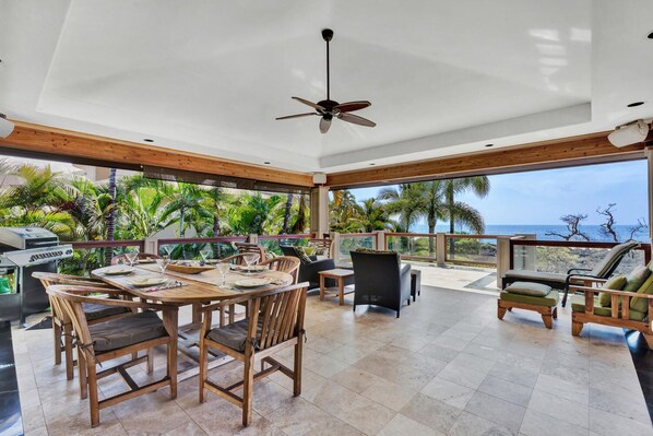 A spacious patio with a dining area, outdoor seating, and a view of the ocean. - 🏖️Great Location | Ocean Front Island Home | Pool | Gated (Kailua Kona)