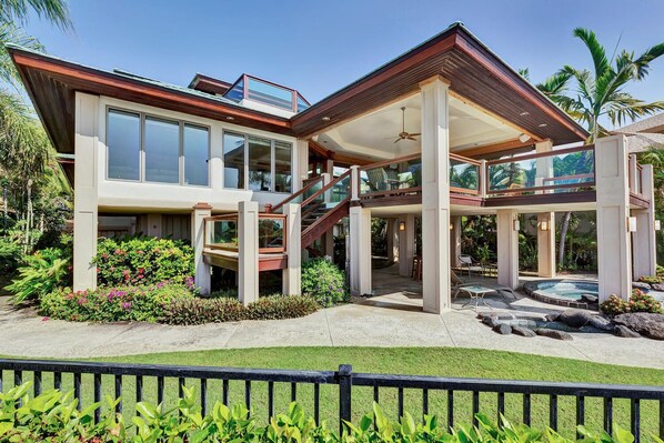 A modern two-story house with a covered patio, a swimming pool, and lush landscaping.