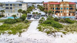 Un hotel frente a la playa con varios balcones, piscina y zona de playa.