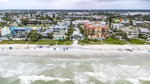 An aerial view of a coastal town with buildings, a beach, and waves.