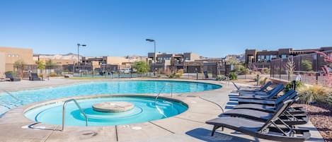 Une piscine avec un jacuzzi circulaire, des chaises longues et un ciel d’un bleu limpide.