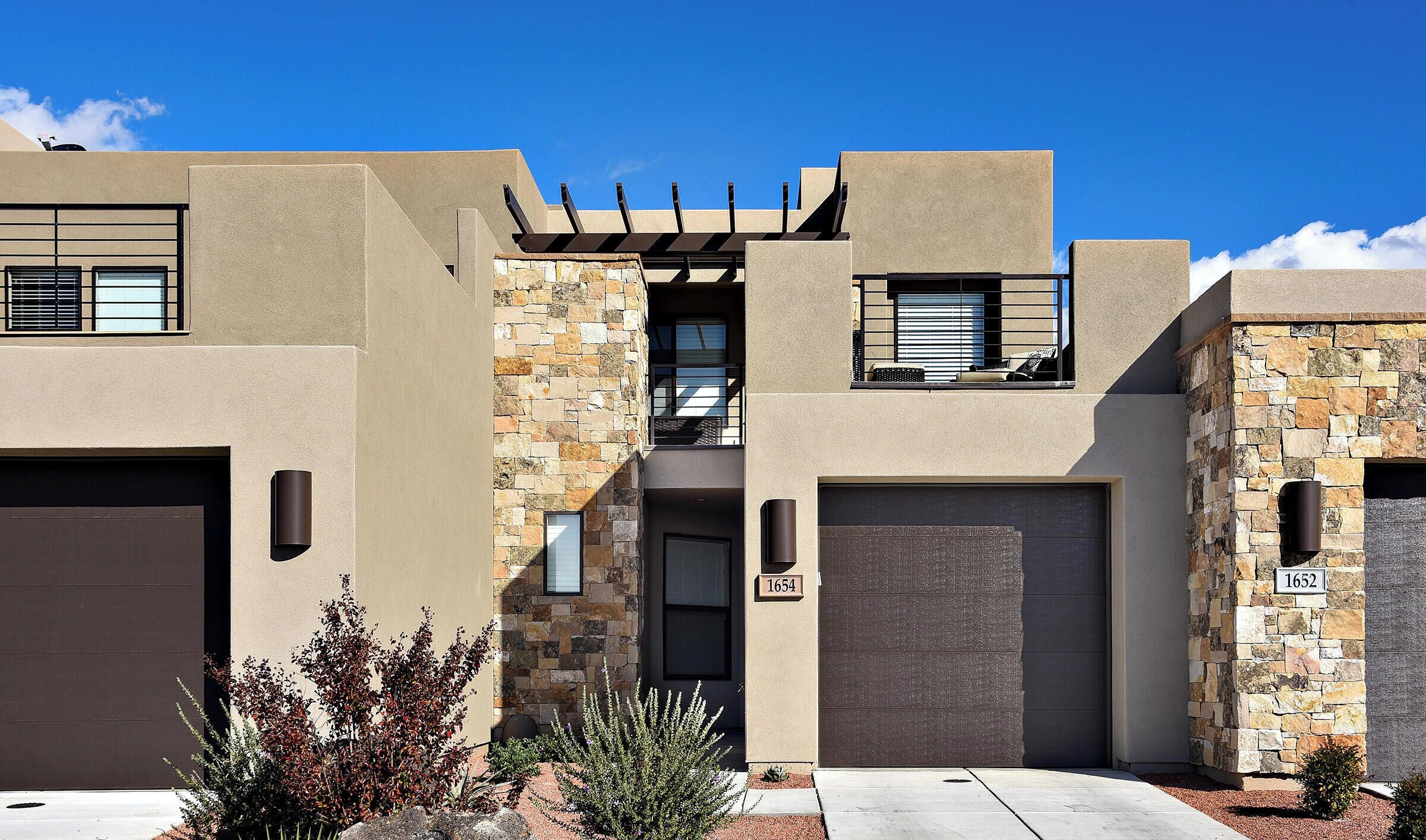 A modern two-story house with a stone facade, a garage, and a well-maintained front yard with landscaping.