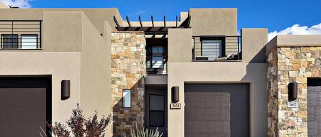 A modern two-story house with a stone facade, a garage, and a well-maintained front yard with landscaping.