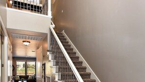A multi-level home interior with a staircase, a living area with a sofa, and a view of the outdoors.
