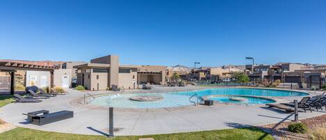 A swimming pool area with lounge chairs and a covered seating area.