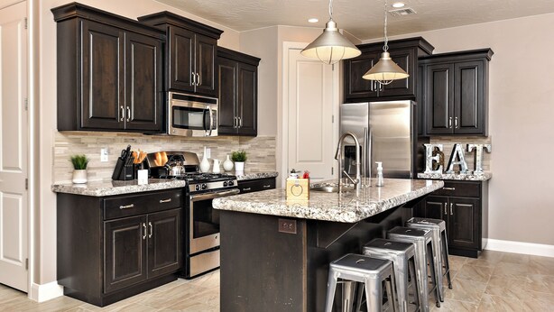A modern kitchen with dark cabinetry, stainless steel appliances, and a central island with bar stools.