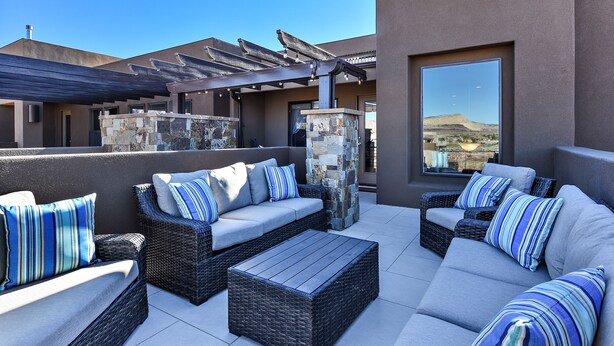 Une terrasse sur le toit, aménagée avec des meubles en osier, des éléments décoratifs en pierre et une pergola.