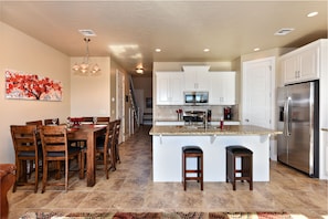 Kitchen View - The Kitchen and Dining Table can accommodate 10 adults and is stocked with pots, pans, baking sheets, mixing bowls, plates, bowls, cups, silverware, and a collection of cooking utensils.