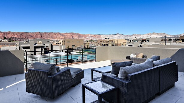 A rooftop patio with outdoor furniture, a swimming pool, and a view of mountains. - Spacious 4BR on the 9th - Overlooks Pool & Courts (St. George)