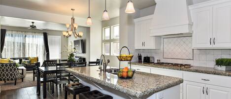 A modern kitchen with white cabinetry, a granite countertop, and a central island with bar stools.