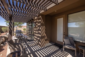 Eine überdachte Terrasse mit Gartenmöbeln, einer Pergola und Blick auf die umliegende Landschaft.