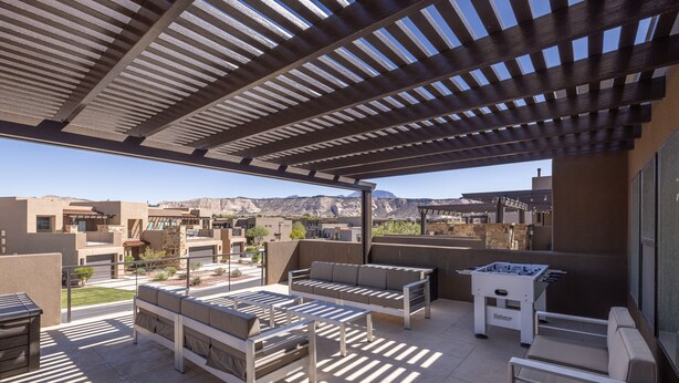 Patio esterno con posti a sedere e tavolo da calcio, affacciato su un paesaggio montuoso.