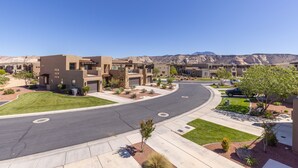 Una zona residenziale moderna con una strada curva, case a tetti piani e una catena montuosa sullo sfondo.