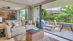 A spacious living area with a sofa, coffee table, and a balcony with a table and chairs.