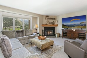 Relax in this inviting living room with a scenic mountain view, comfortable seating, and a warm fireplace.