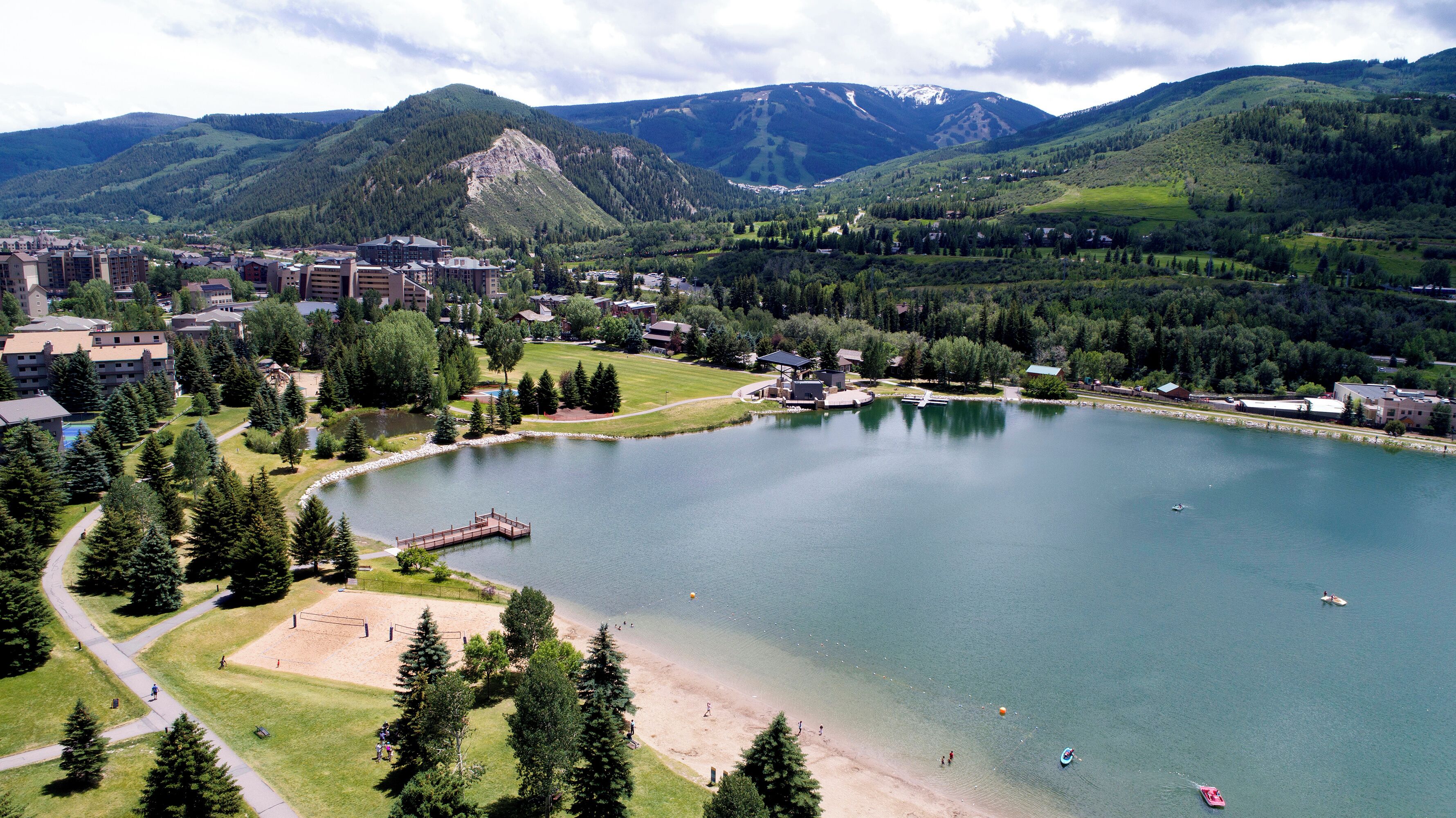 Ein Seehotel mit Steg, Strand und Bergpanorama.