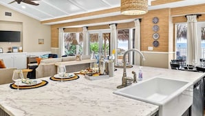 A modern kitchen with a large island, a ceiling fan, and a view to the outside. - Gulf Front Dreams Beachfront Home in Clearwater (Clearwater Beach)