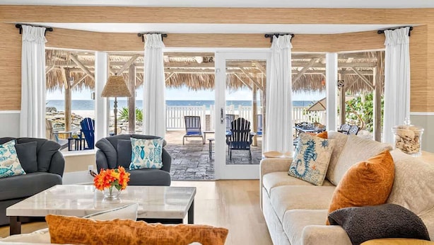 A living room with a view of the beach, furnished with sofas and a coffee table. - Gulf Front Dreams Beachfront Home in Clearwater (Clearwater Beach)