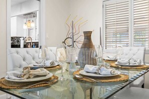 A dining table set with plates, cutlery, and glassware, with a vase and decorative branches on the table.