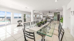 A spacious dining area with a glass table and chairs, large windows with a view of the sea, and a modern kitchen in the background. - Florida Villa - Waterfront - Private Pool! (Crystal Beach)