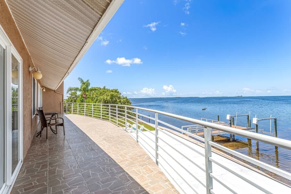Ein Balkon mit Meerblick, einer Brüstung und einem Tisch mit Stühlen.