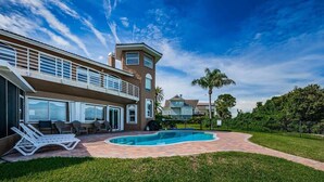 A two-story house with a swimming pool, outdoor seating, and a well-maintained lawn. - Florida Villa - Waterfront - Private Pool! (Crystal Beach)