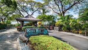 A sign for Kona Bay Estates with a gazebo and lush greenery.
