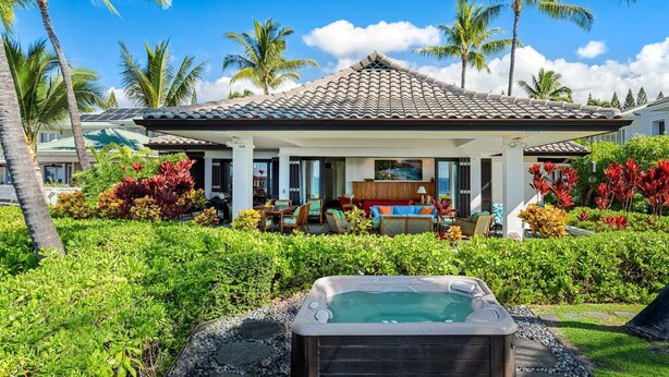 A house with a tiled roof, a patio with outdoor furniture, and a hot tub.
