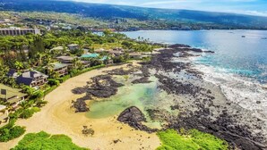 A coastal resort with a sandy beach, clear waters, and lush greenery.