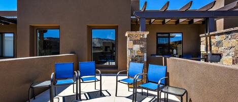 A rooftop patio with blue chairs and a stone wall.