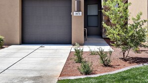 A modern two-story building with a garage, a balcony with blue chairs, and a stone accent wall. - Stylish 4BR on the 18th - Rooftop Deck, Near Pool (St. George)