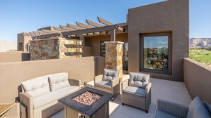 Une terrasse sur le toit, aménagée avec des meubles en osier, un foyer et un mur en pierre.
