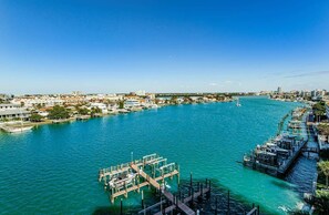 A waterfront cityscape with a marina, buildings, and a clear blue sky.
