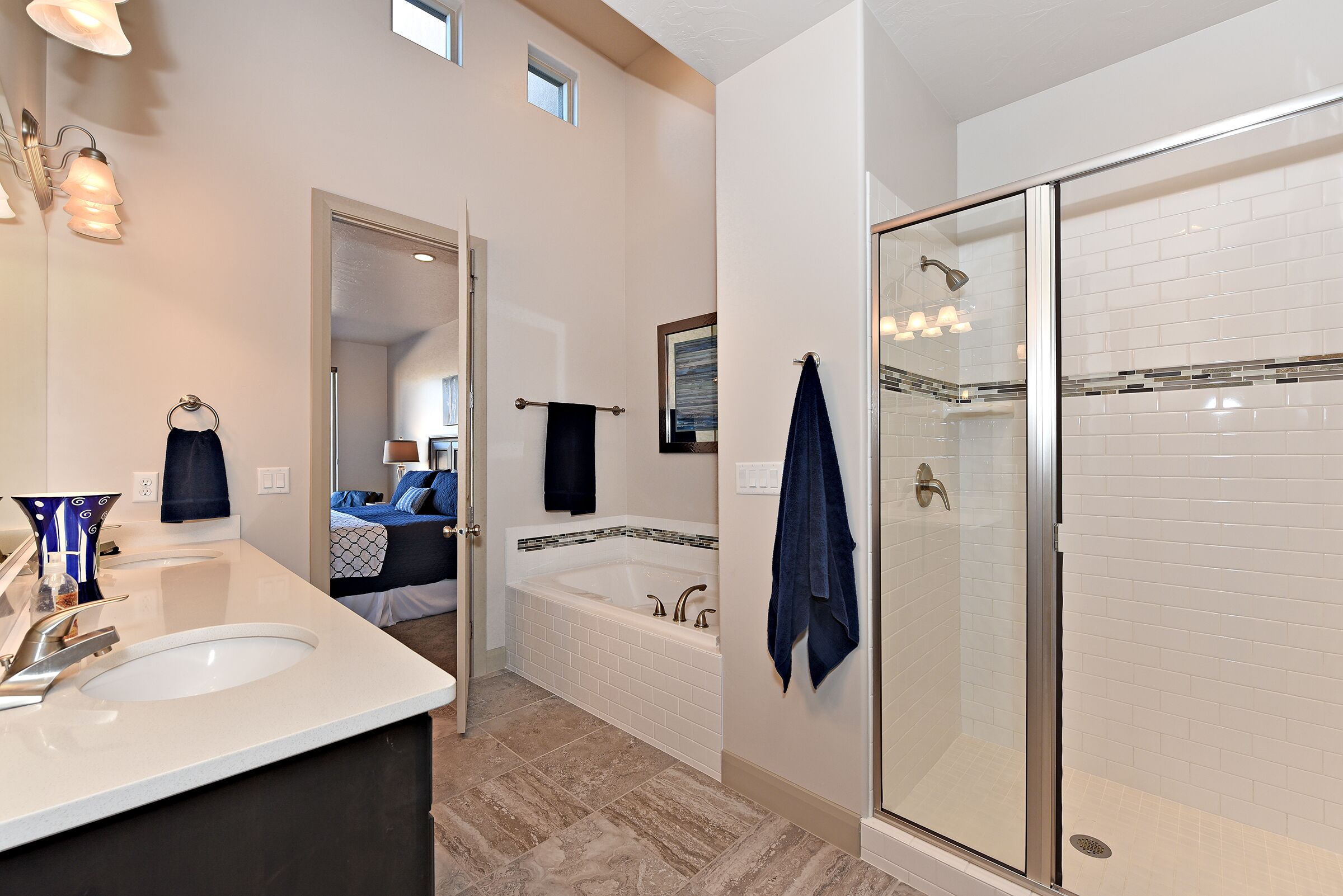 A modern bathroom with two sinks, a bathtub, and a glass-enclosed shower.