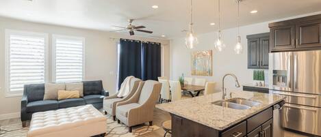 A modern kitchen with a central island, stainless steel appliances, and pendant lighting.