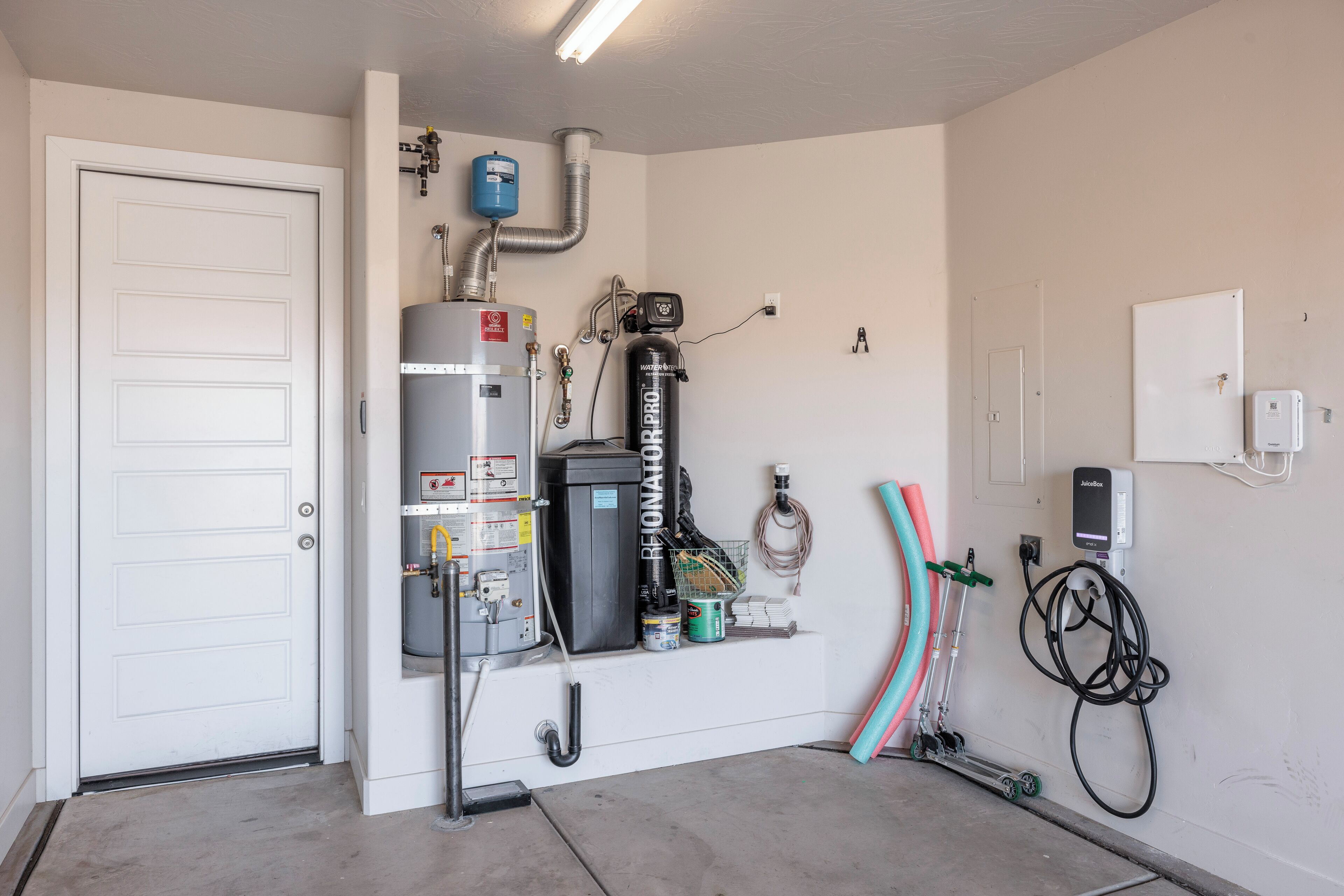 A utility room with a water heater, a water filter, and a water pump.