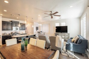 Een moderne keuken met donkere kasten, een centraal eiland en een eethoek met een houten tafel en stoelen.