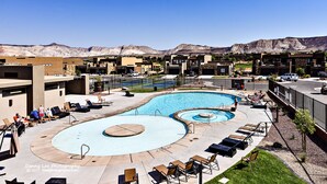 A pool area with multiple swimming pools, lounge chairs, and a view of mountains in the background.
