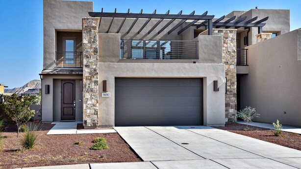 A modern two-story house with a garage, stone accents, and a clear view of the mountains in the background.