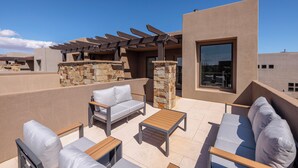 Une terrasse sur le toit avec des sièges extérieurs, une pergola et un mur en pierre.